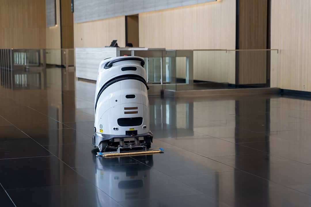 An automated floor robot cleaning the lobby floor of a modern office.
